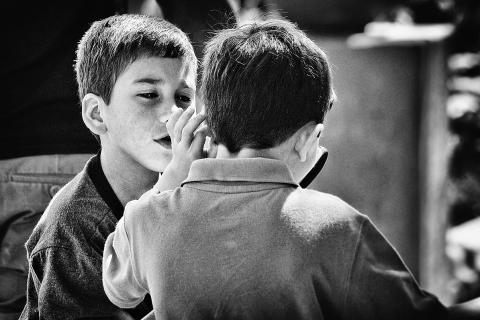A boy whispering to his friend. The Thai for "a boy whispering to his friend" is "เด็กผู้ชายกระซิบบอกเพื่อนของเขา".