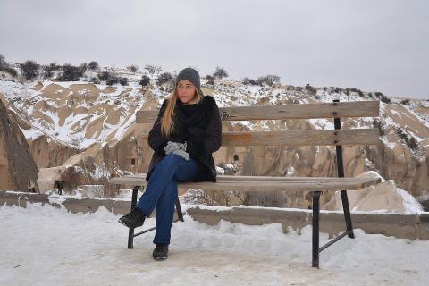 A woman sitting cross-legged on a bench. The Thai for "a woman sitting cross-legged on a bench" is "ผู้หญิงนั่งไขว่ห้างบนม้านั่ง".