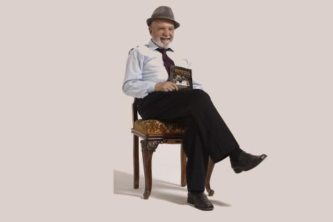 An old man sitting cross-legged on a chair. The Thai for "an old man sitting cross-legged on a chair" is "ชายชรานั่งไขว่ห้างบนเก้าอี้".