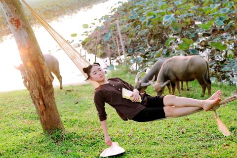 A woman napping in a hammock. The Thai for "a woman napping in a hammock" is "ผู้หญิงงีบหลับอยู่ในเปล".